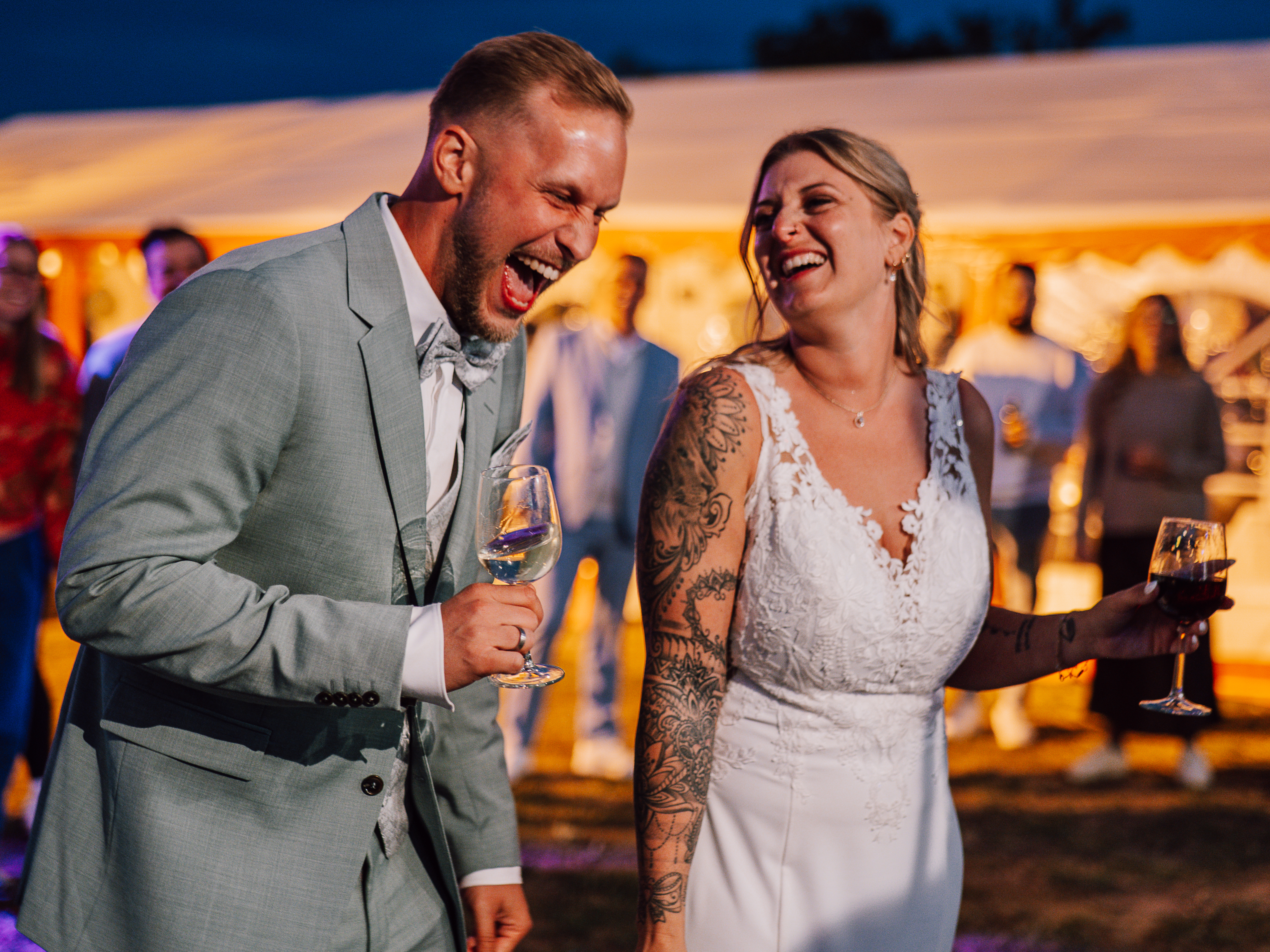 feierndes Brautpaar mit Wein auf Hochzeitsparty